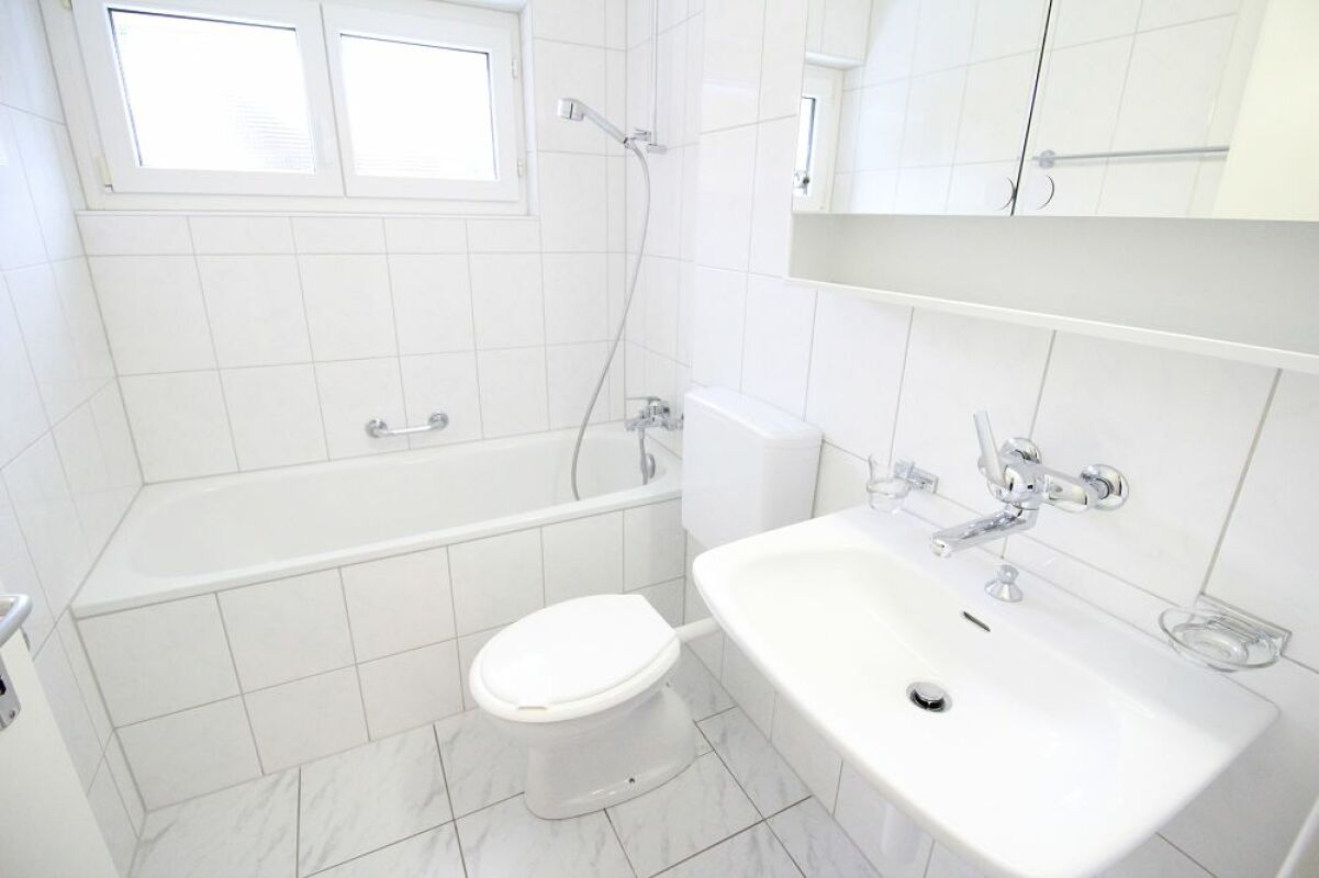 Helles weißes Badezimmer mit Badewanne, Waschbecken und WC