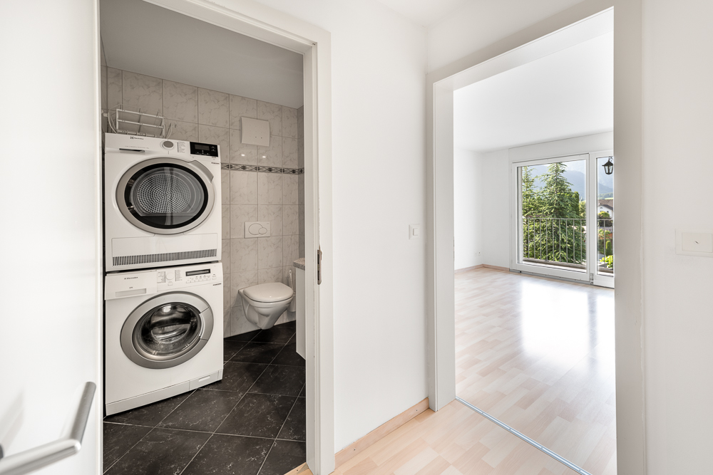 Flur mit Blick auf einen Hauswirtschaftsraum und ein helles Zimmer mit Balkon