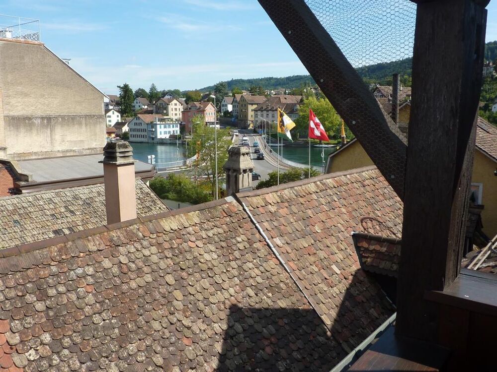 Dachblick über eine historische Altstadt mit Wasser und Hügellandschaft