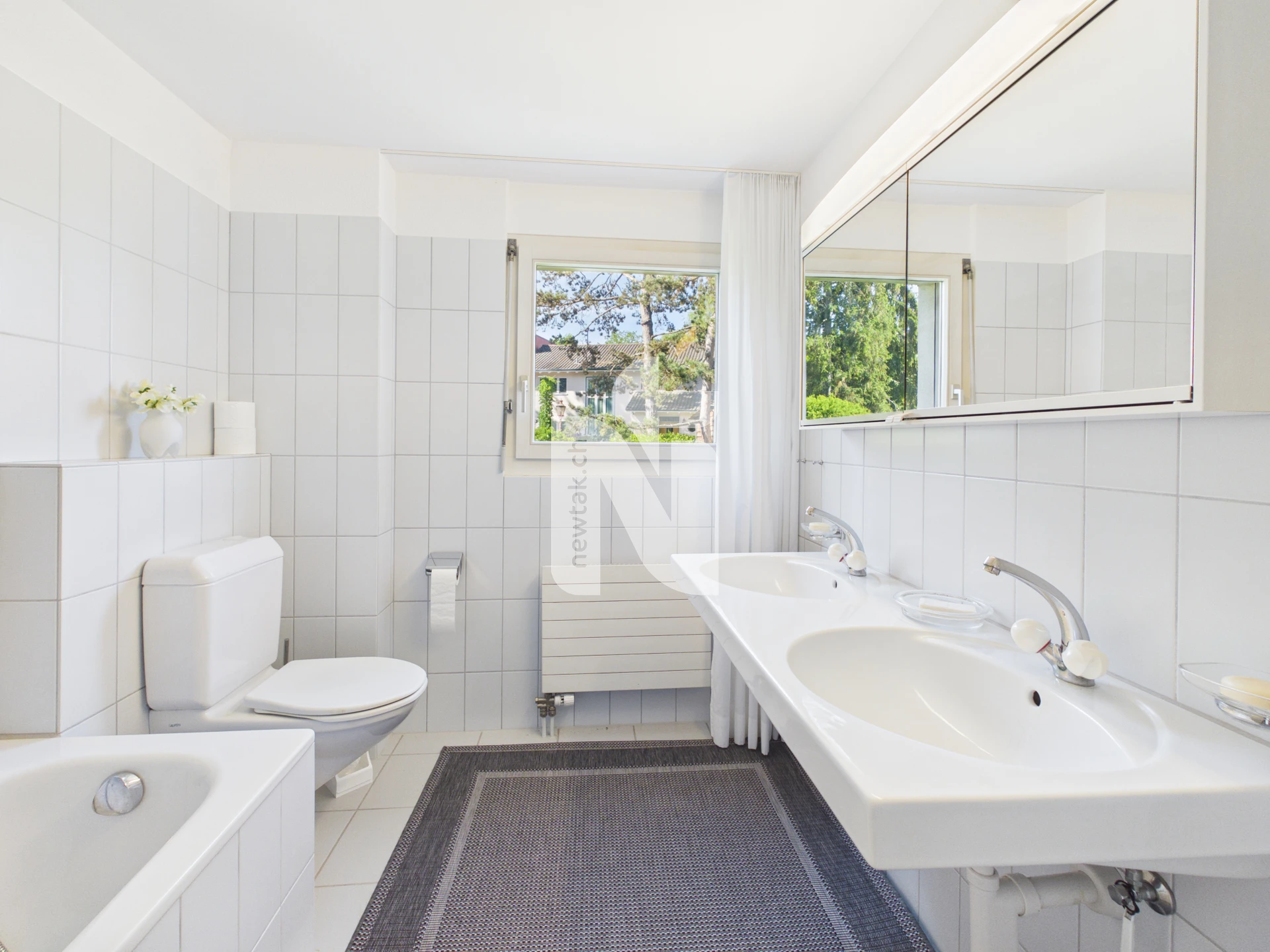 Helles Badezimmer mit Doppelwaschbecken und Badewanne