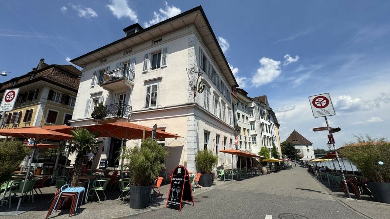 Straßenseite eines historischen Gebäudes mit Außenbestuhlung