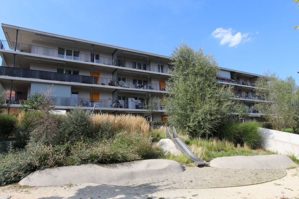 Mehrfamilienhaus mit Spielbereich und Balkonfassade