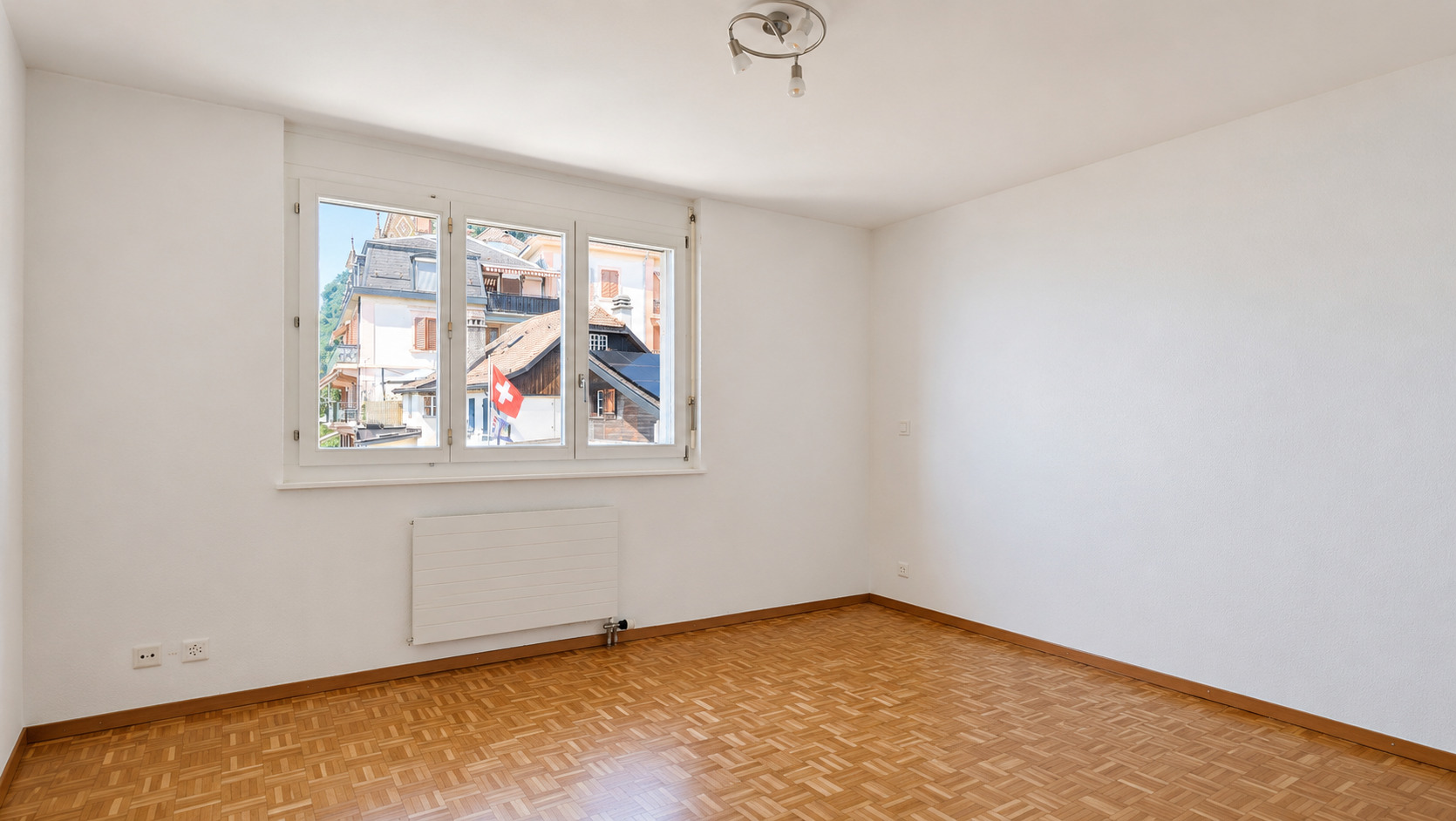 Heller leerer Raum mit Parkett und Fensterblick