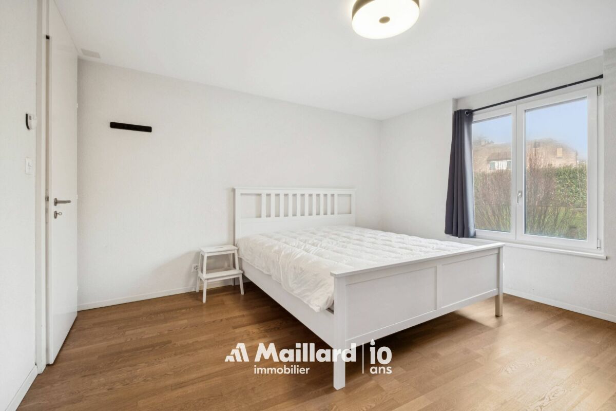 Helles Schlafzimmer mit weißem Bett und Holzfußboden