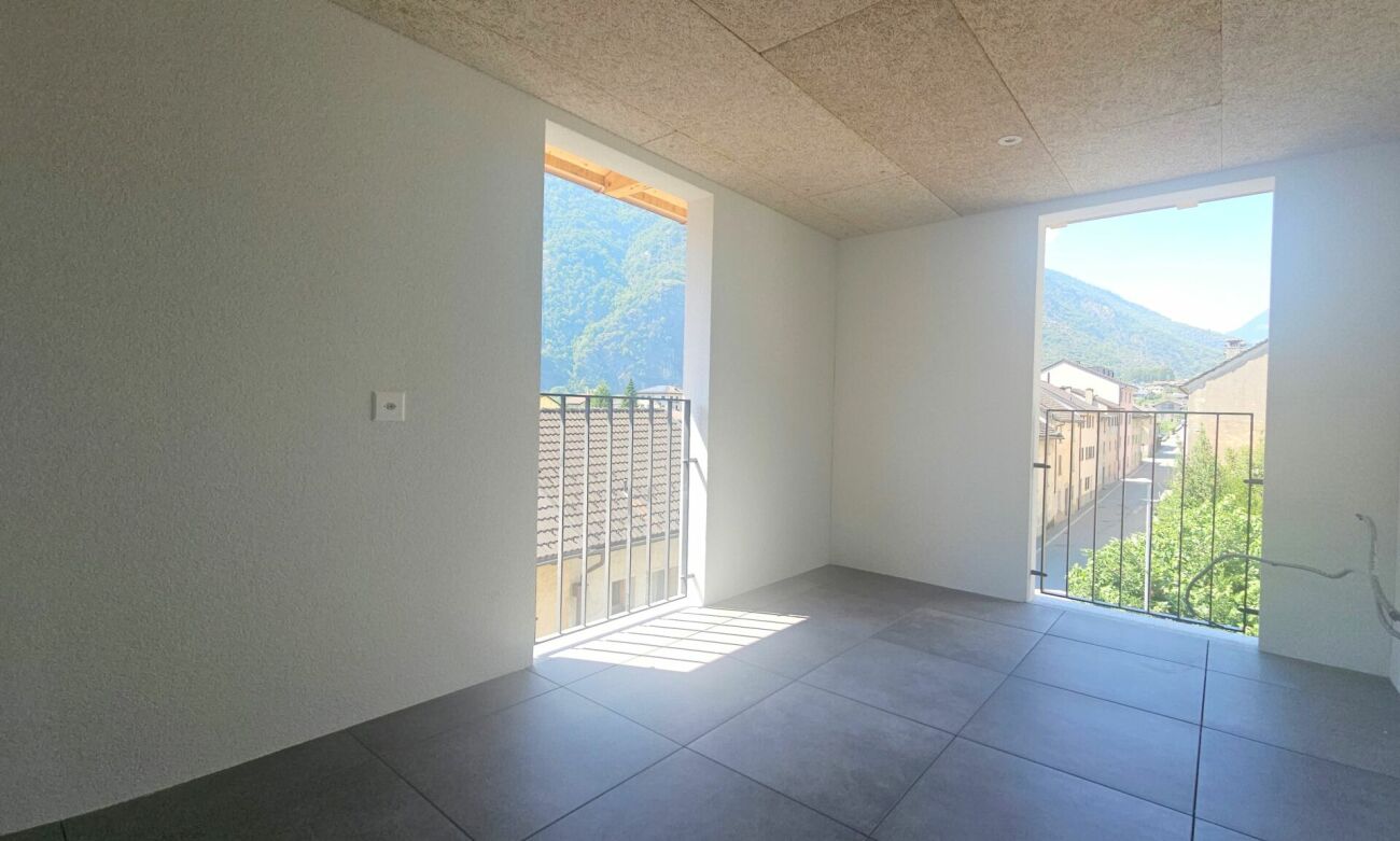 Heller leerer Raum mit Balkonöffnungen und Bergblick