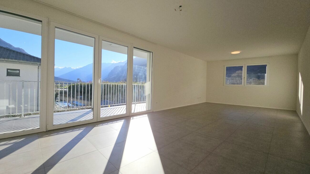 Heller leerer Wohnraum mit großer Fensterfront und Bergblick