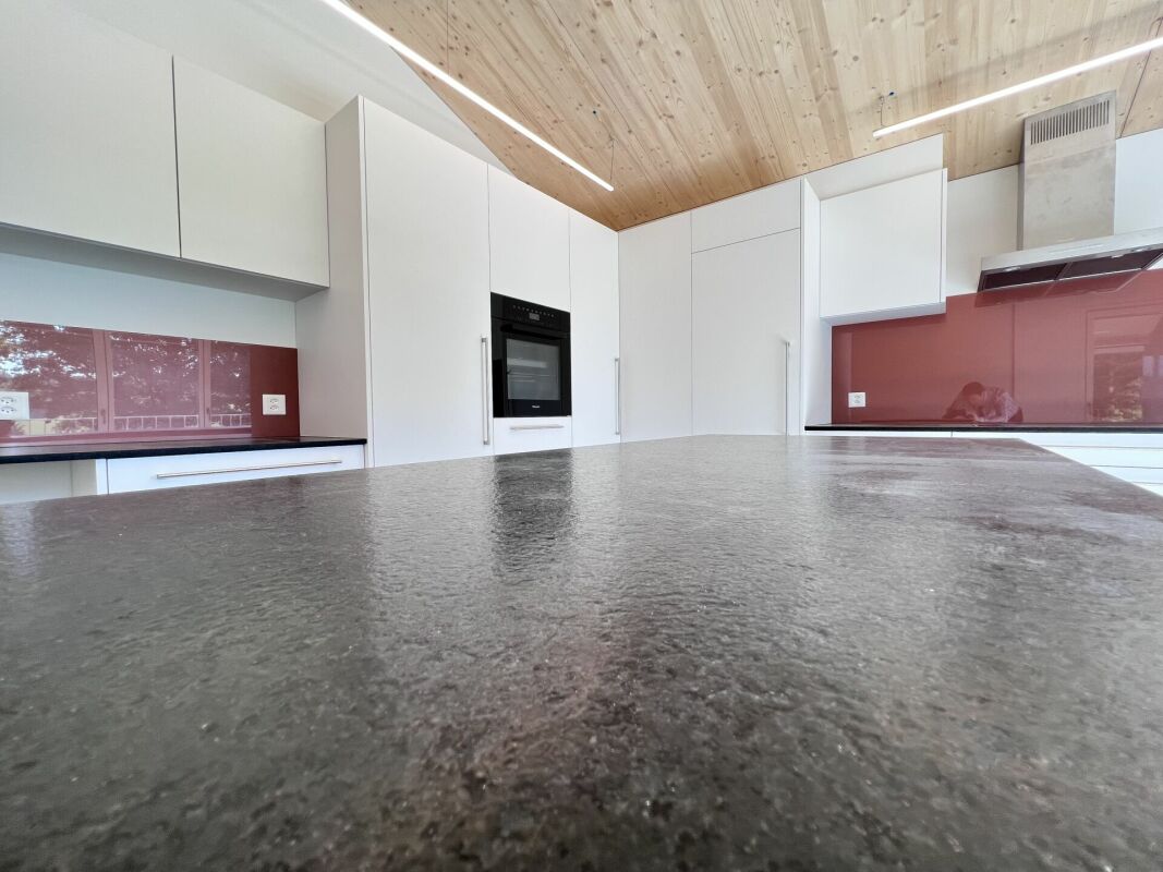 Moderne Küche mit Holzdecke und dunkler Arbeitsfläche