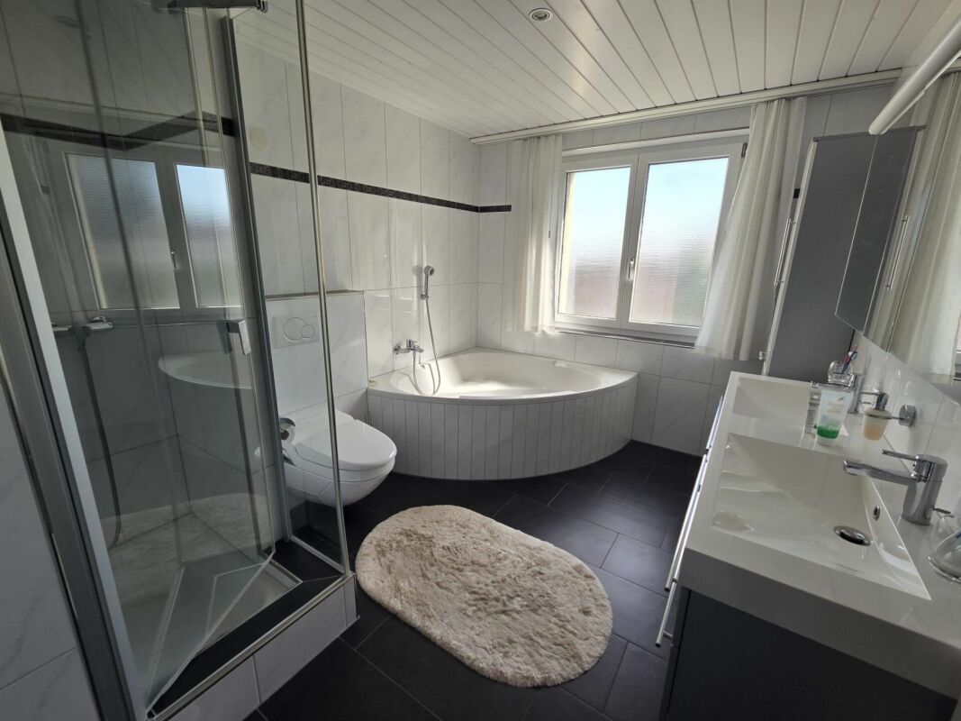 Modernes Badezimmer mit Eckwanne und Glasdusche