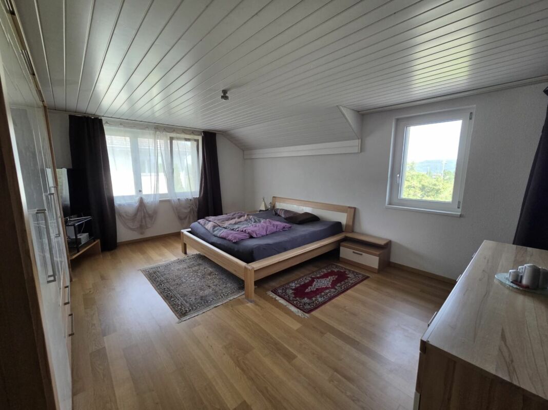 Schlafzimmer mit Dachschräge und zwei Fenstern
