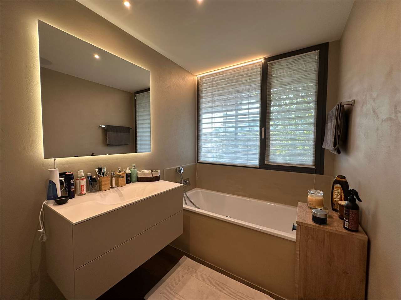 Modernes Badezimmer mit Badewanne und beleuchtetem Spiegel