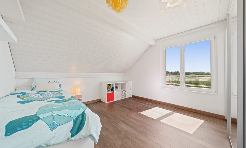 Helles Dachgeschoss-Schlafzimmer mit Fensterblick