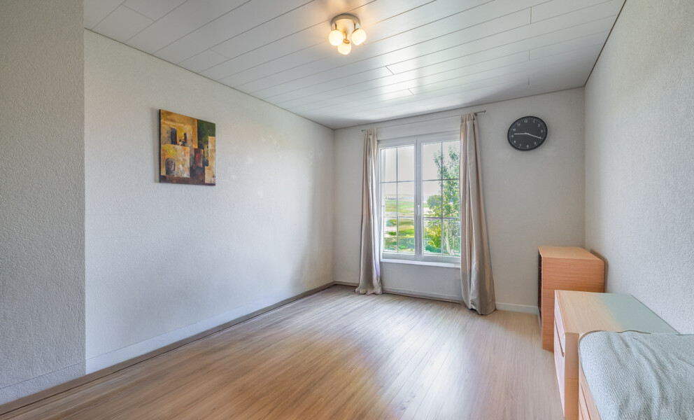 Helles Schlafzimmer mit Fenster und wenigen Möbeln