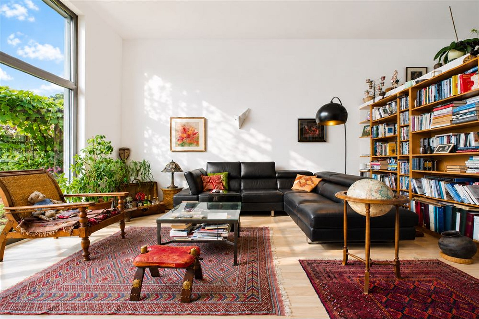 Helles Wohnzimmer mit großer Fensterfront und Bücherwand