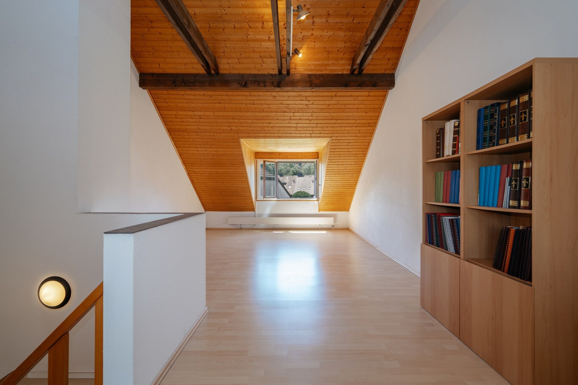 Helles Dachgeschoss mit Sichtbalken und Bücherregal