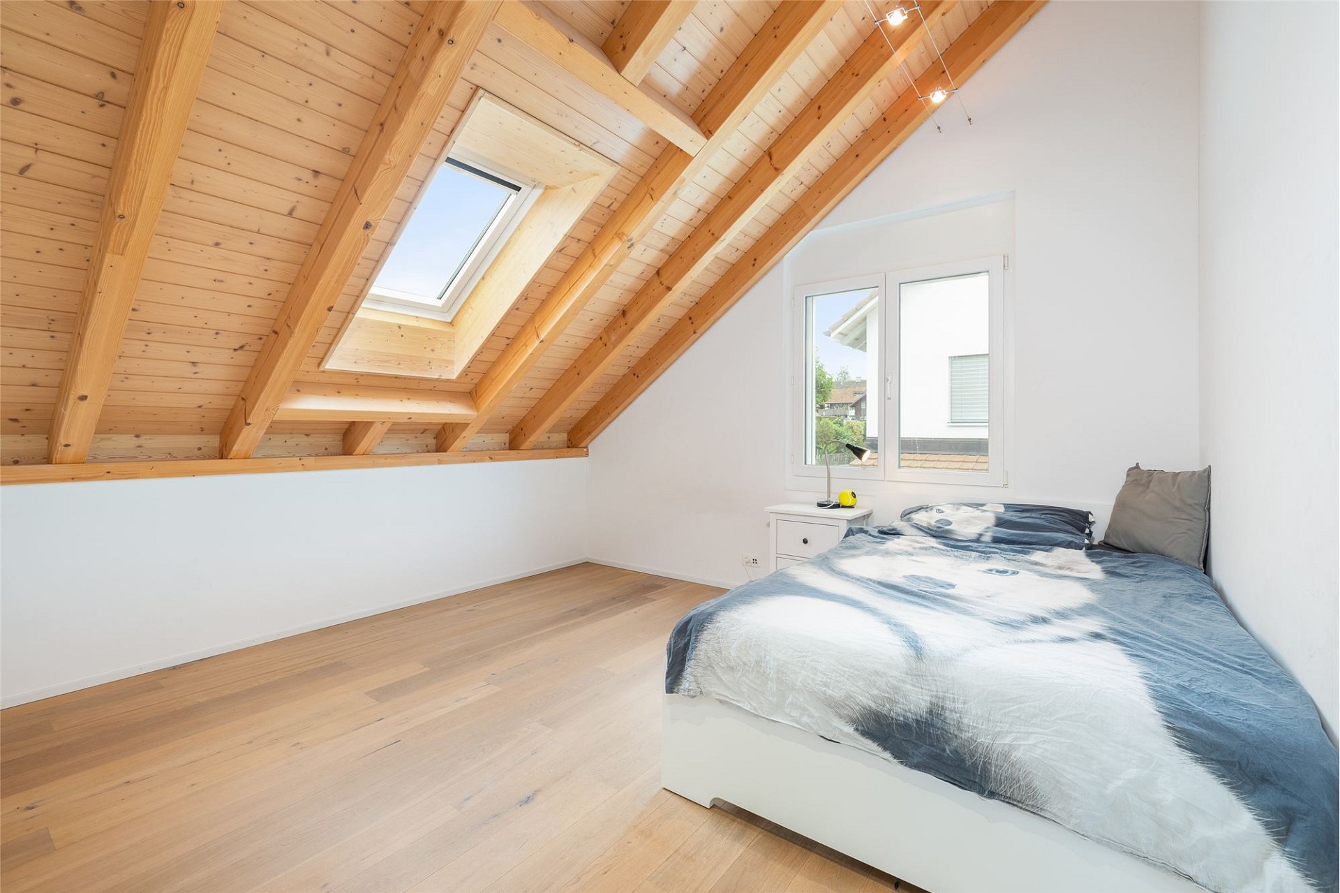 Helles Dachgeschoss-Schlafzimmer mit sichtbaren Holzbalken