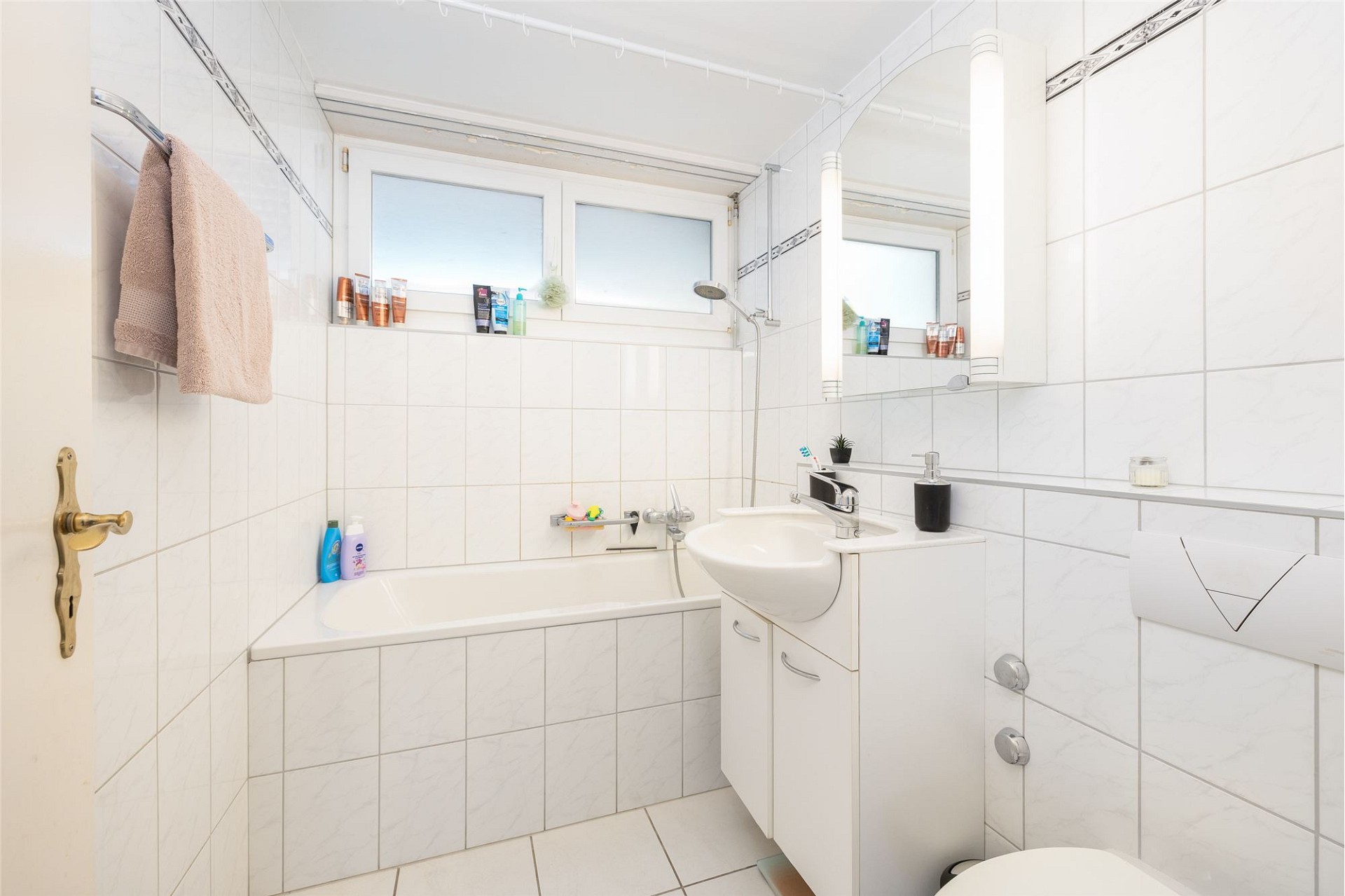 Helles, kleines Badezimmer mit Badewanne und Waschtisch