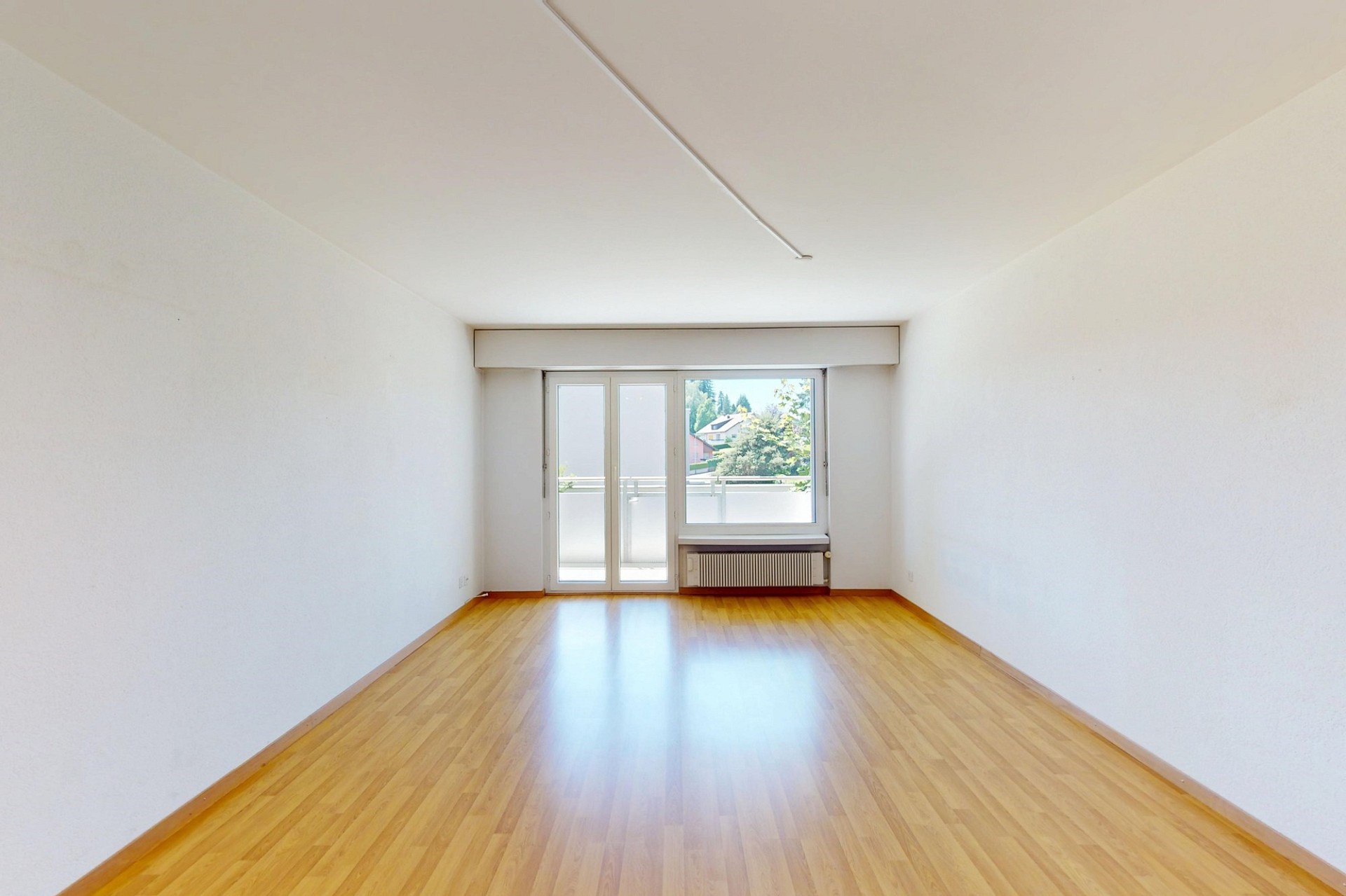 Heller leerer Wohnraum mit Balkon und großem Fenster