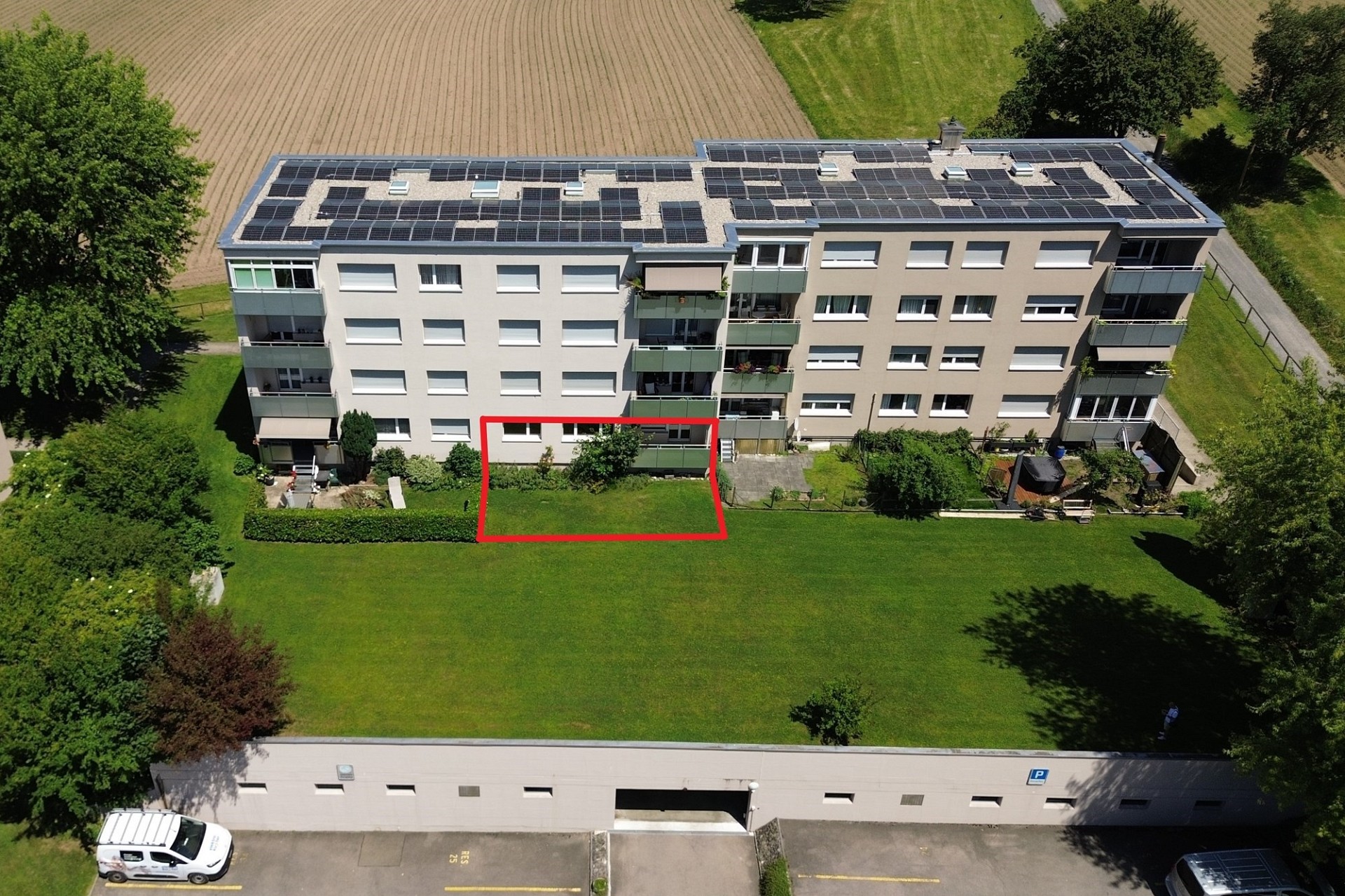 Aerialaufnahme eines Mehrfamilienhauses mit markierter Gartenfläche