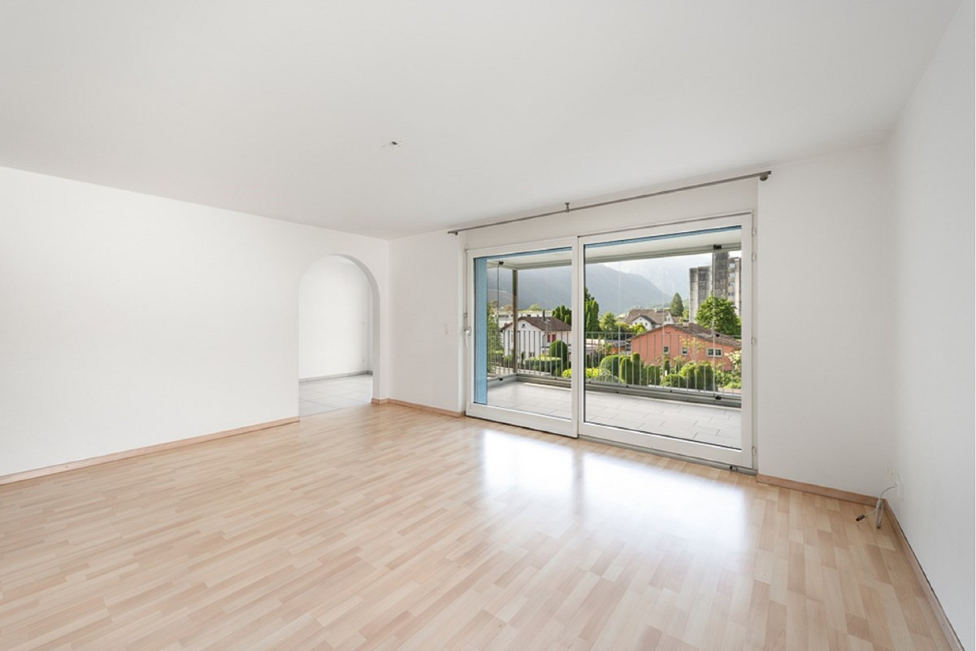 Heller leerer Wohnraum mit Balkonzugang und Blick ins Freie