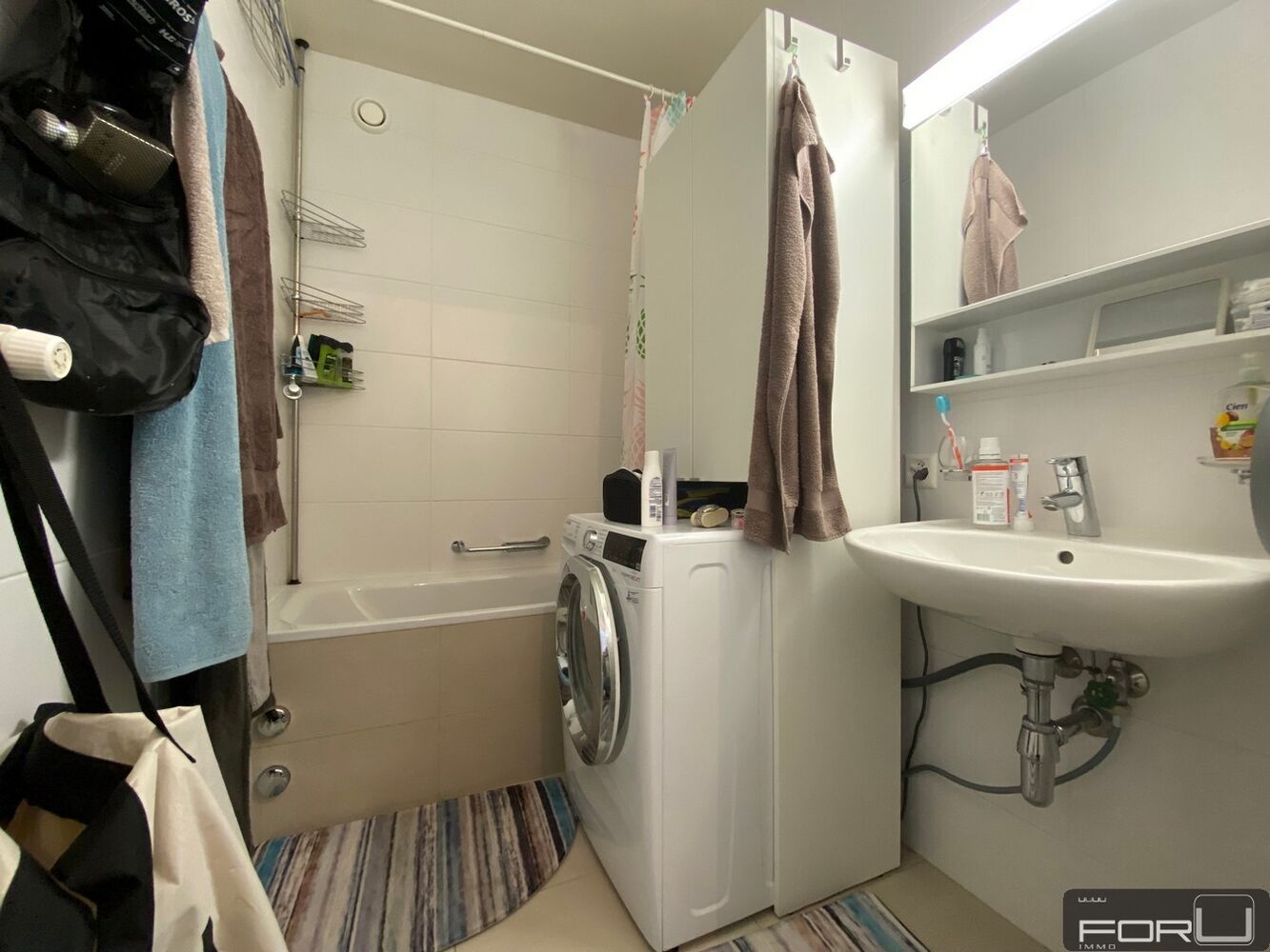 Kleines Badezimmer mit Badewanne, Waschmaschine und Waschbecken