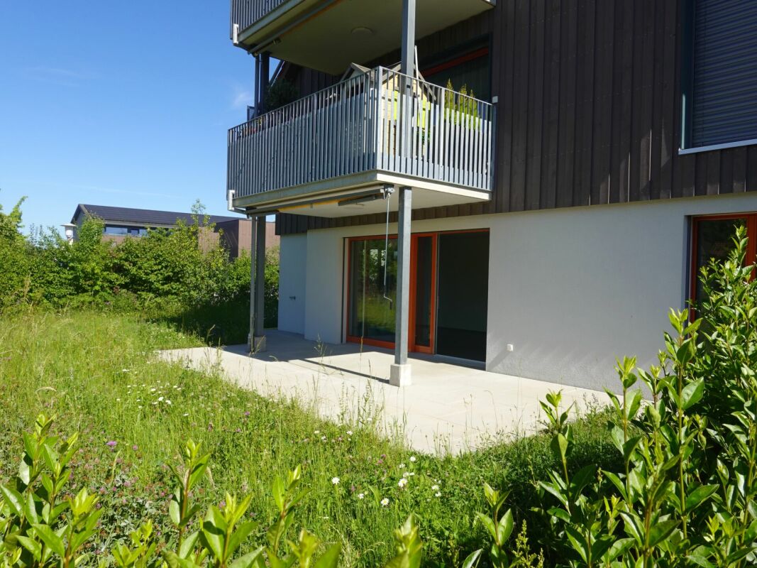 Außenansicht eines modernen Wohngebäudes mit Balkon und Garten