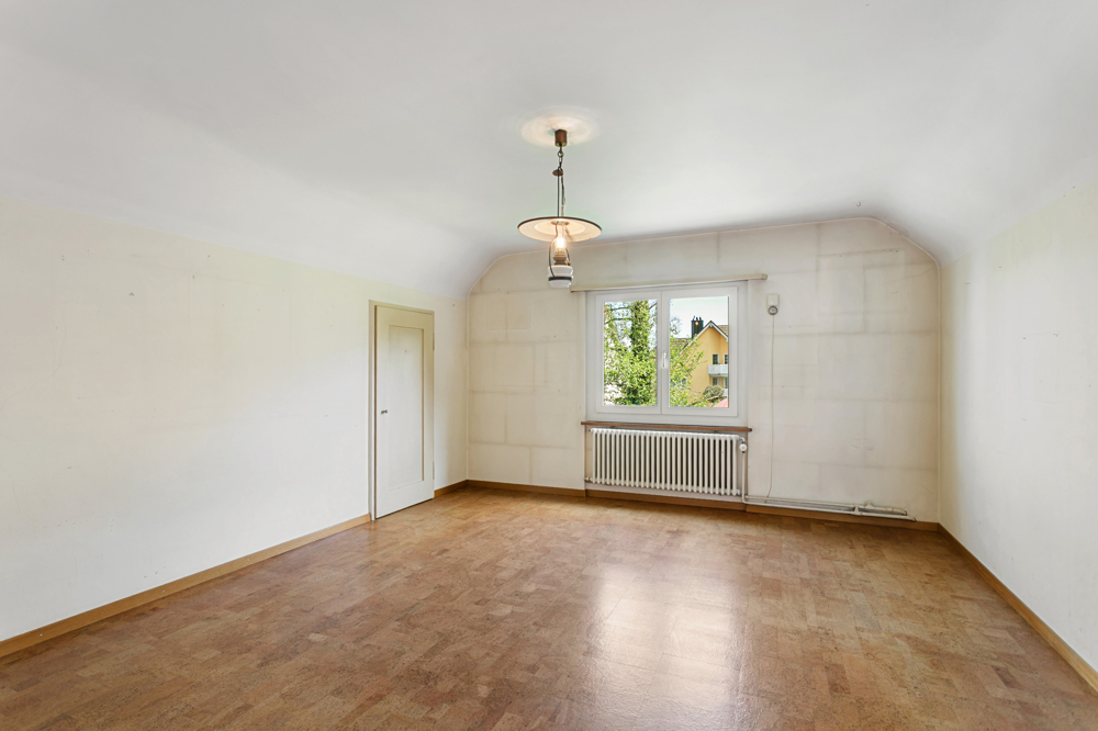 Leeres Dachzimmer mit Fenster und Heizkörper