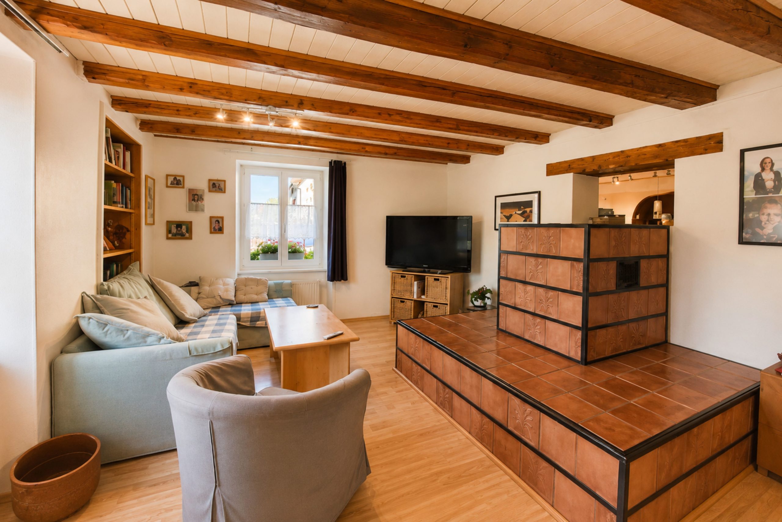 Gemütliches Wohnzimmer mit Holzbalkendecke und Kaminofen