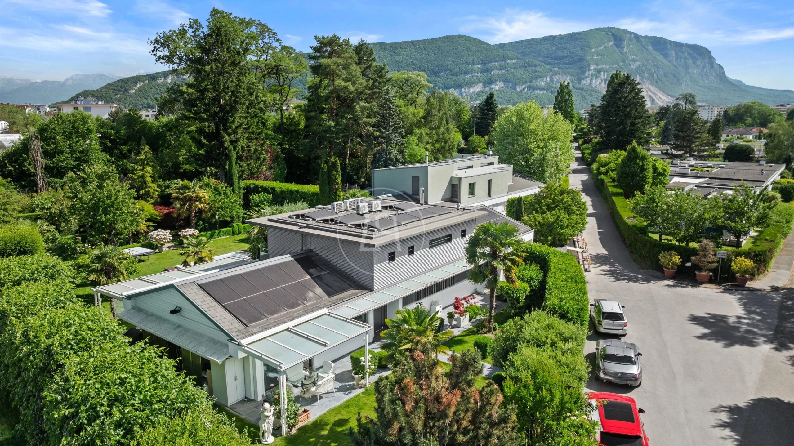 Luftaufnahme eines modernen Wohnhauses in grüner Hanglage mit Bergpanorama