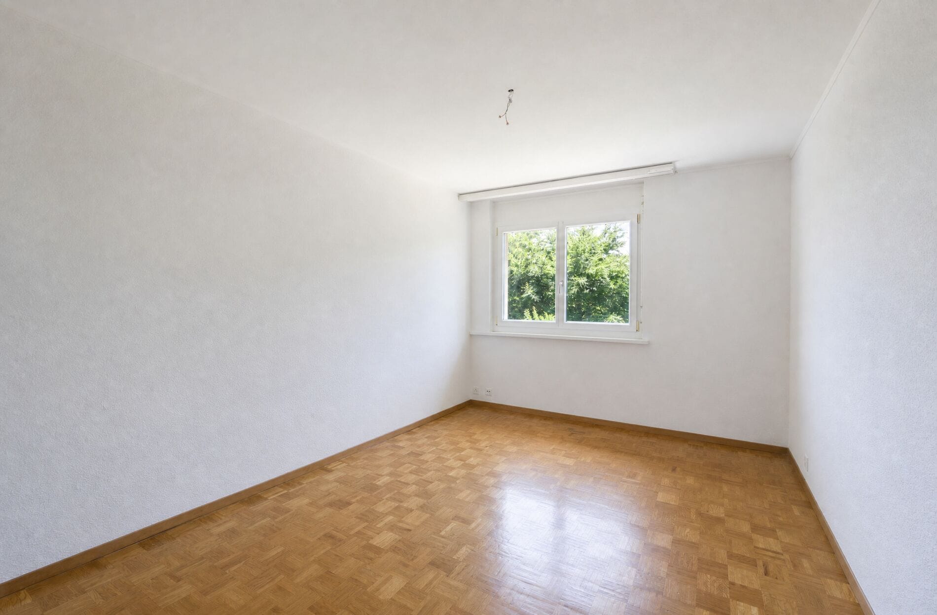 Leerer heller Raum mit Parkett und Fenster