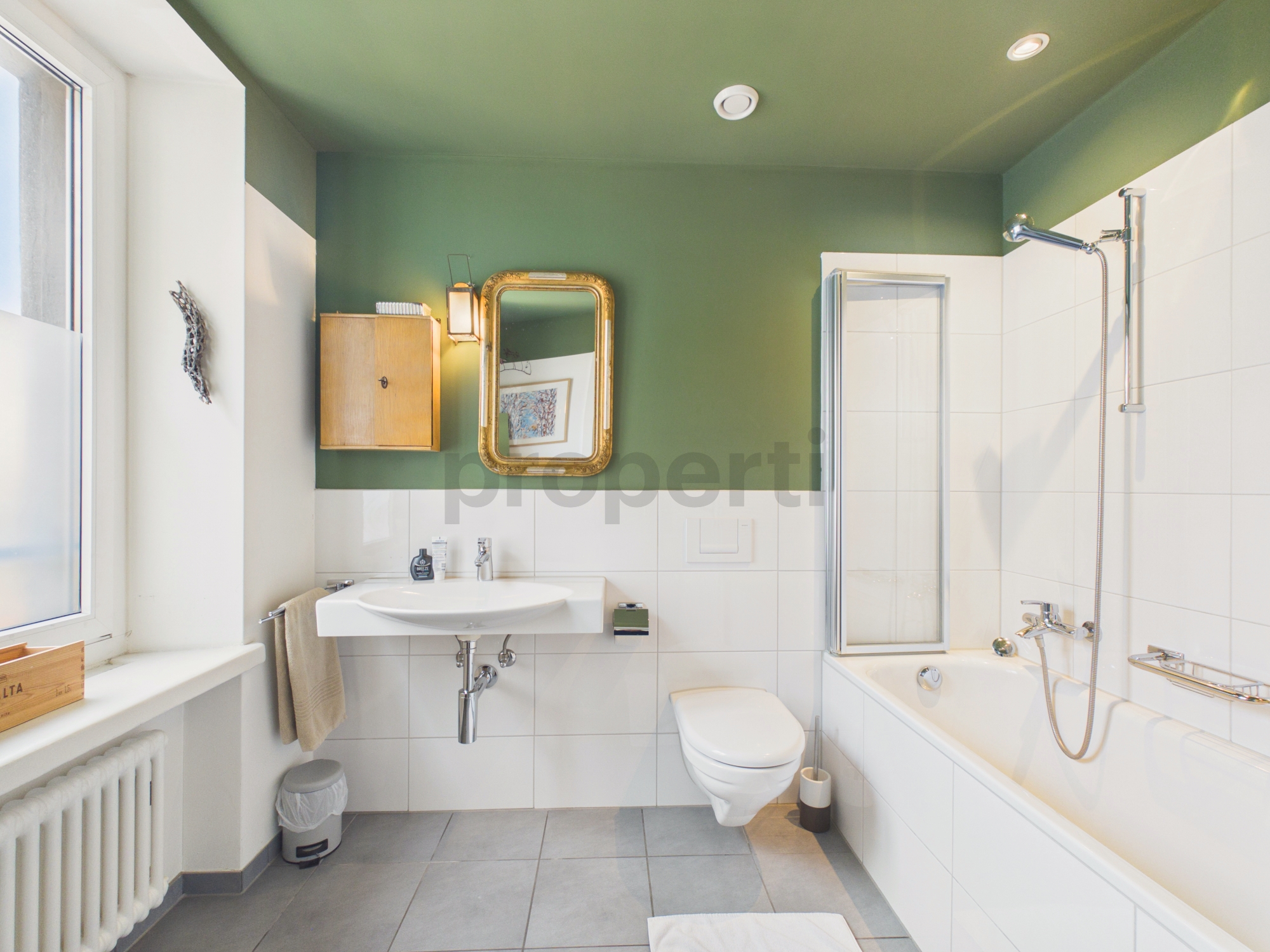Helles Badezimmer mit Badewanne und grüner Akzentwand