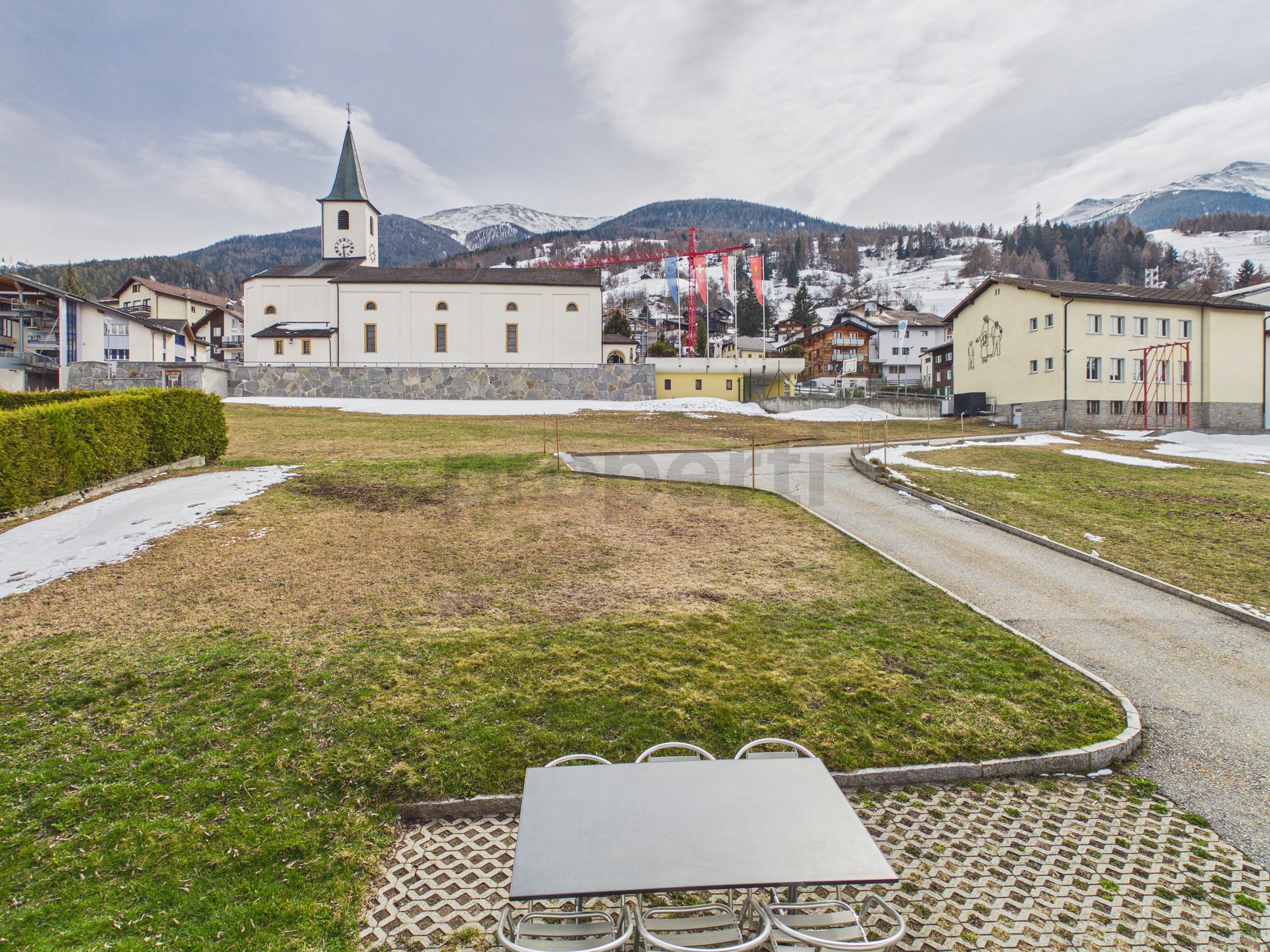 Außenansicht eines alpinen Orts mit Kirche und Blick auf Berge