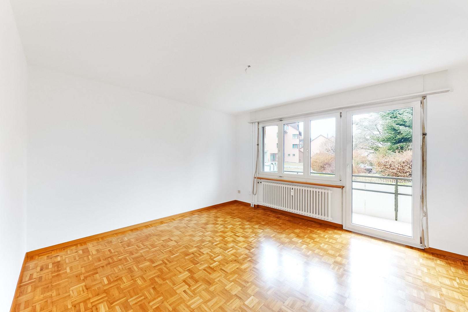 Heller leerer Wohnraum mit Balkon und Parkettboden
