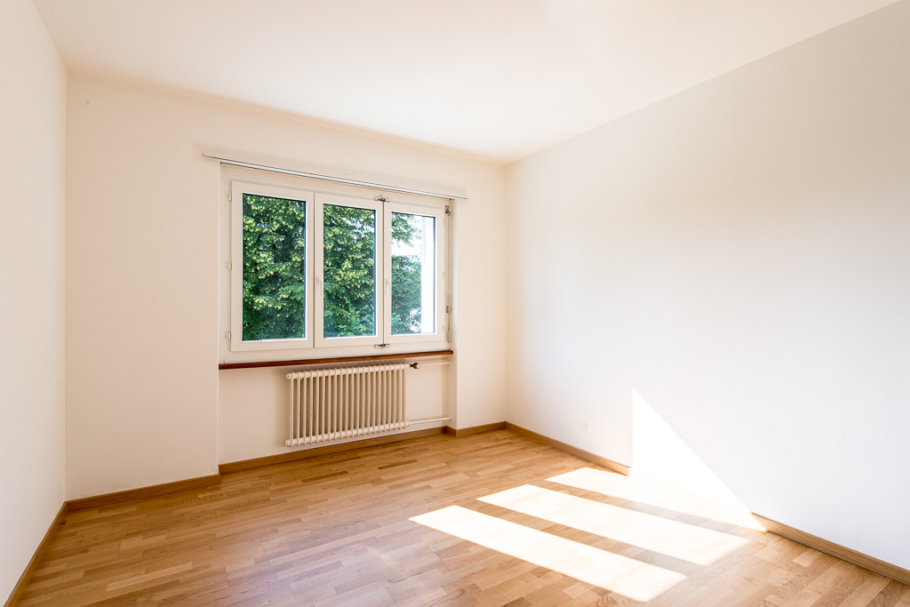 Helles, leeres Zimmer mit Fenster und Heizkörper