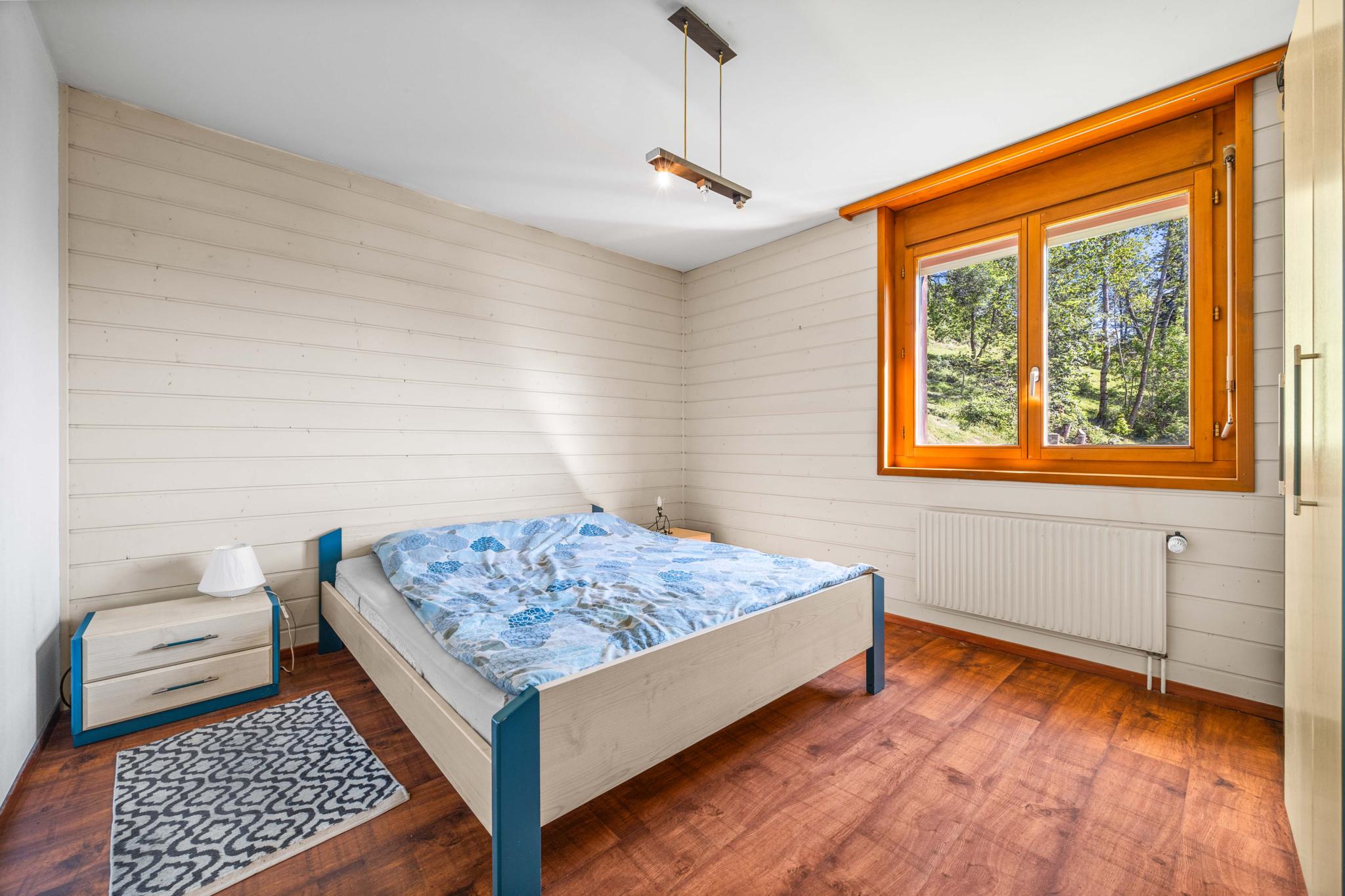 Helles Schlafzimmer mit Holzfenster und Waldblick