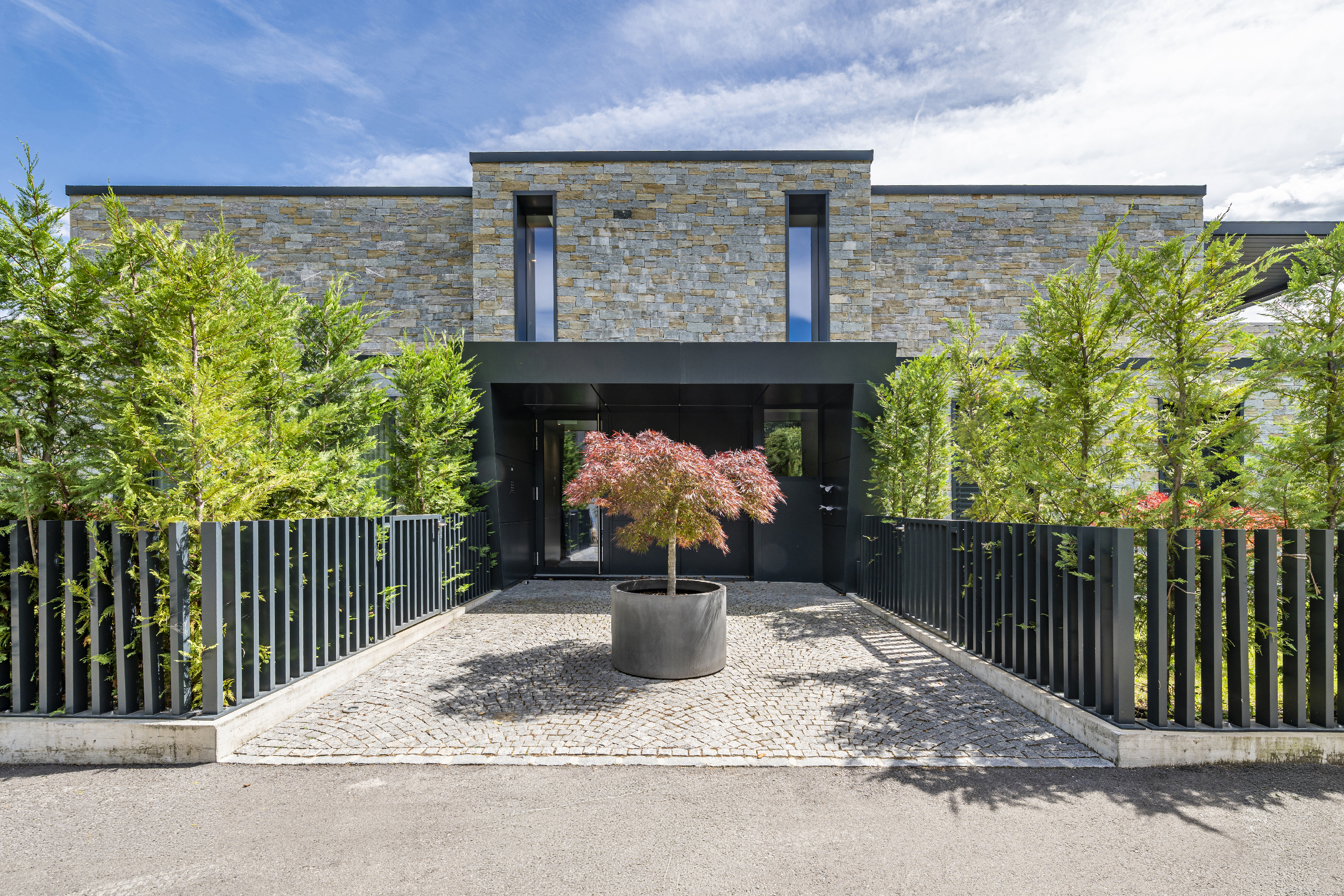 Moderne Villenfassade mit Naturstein und Eingangshof