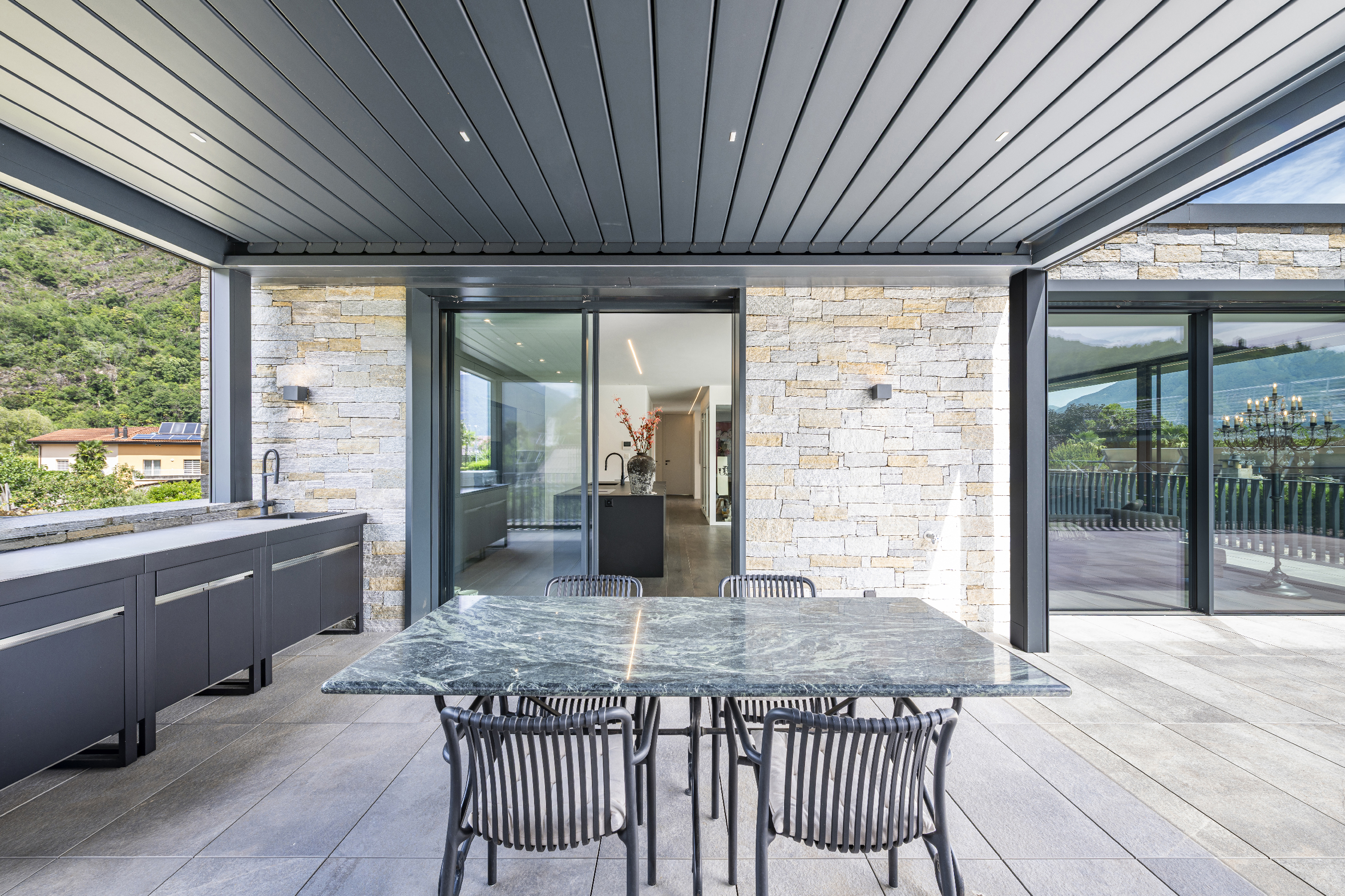 Moderne überdachte Terrasse mit Outdoor-Küche
