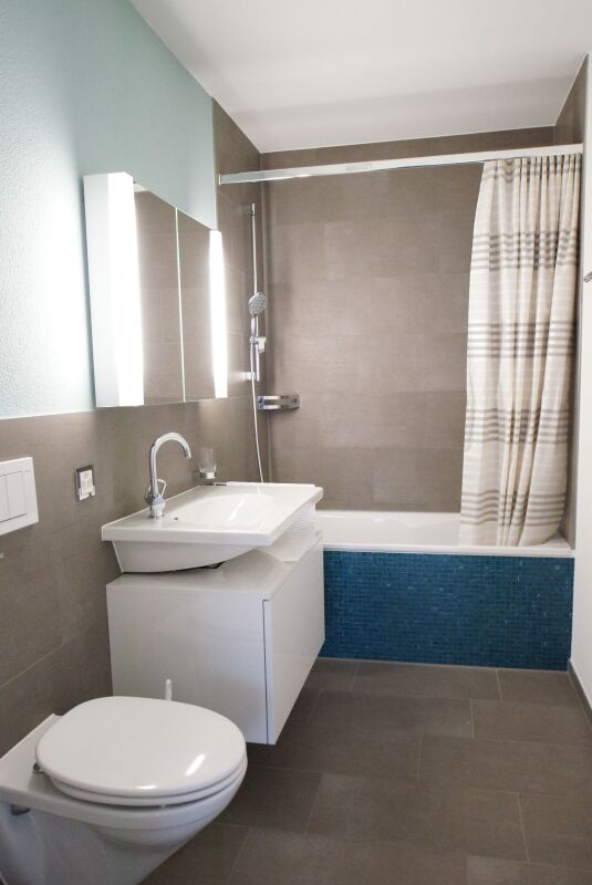 Modernes Badezimmer mit Badewanne und blauem Fliesendetail