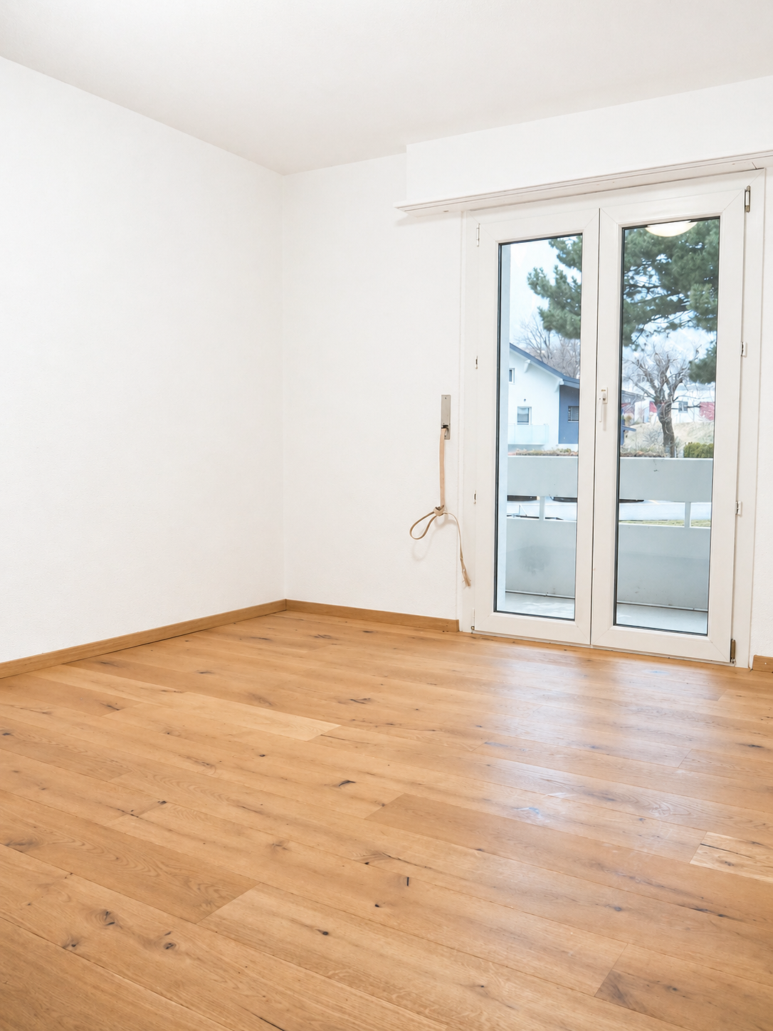 Leerer heller Raum mit Holzboden und Balkontür