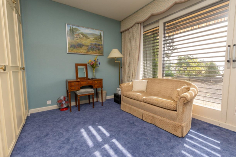 Helles Schlafzimmer mit blauem Teppich und Sitzbereich