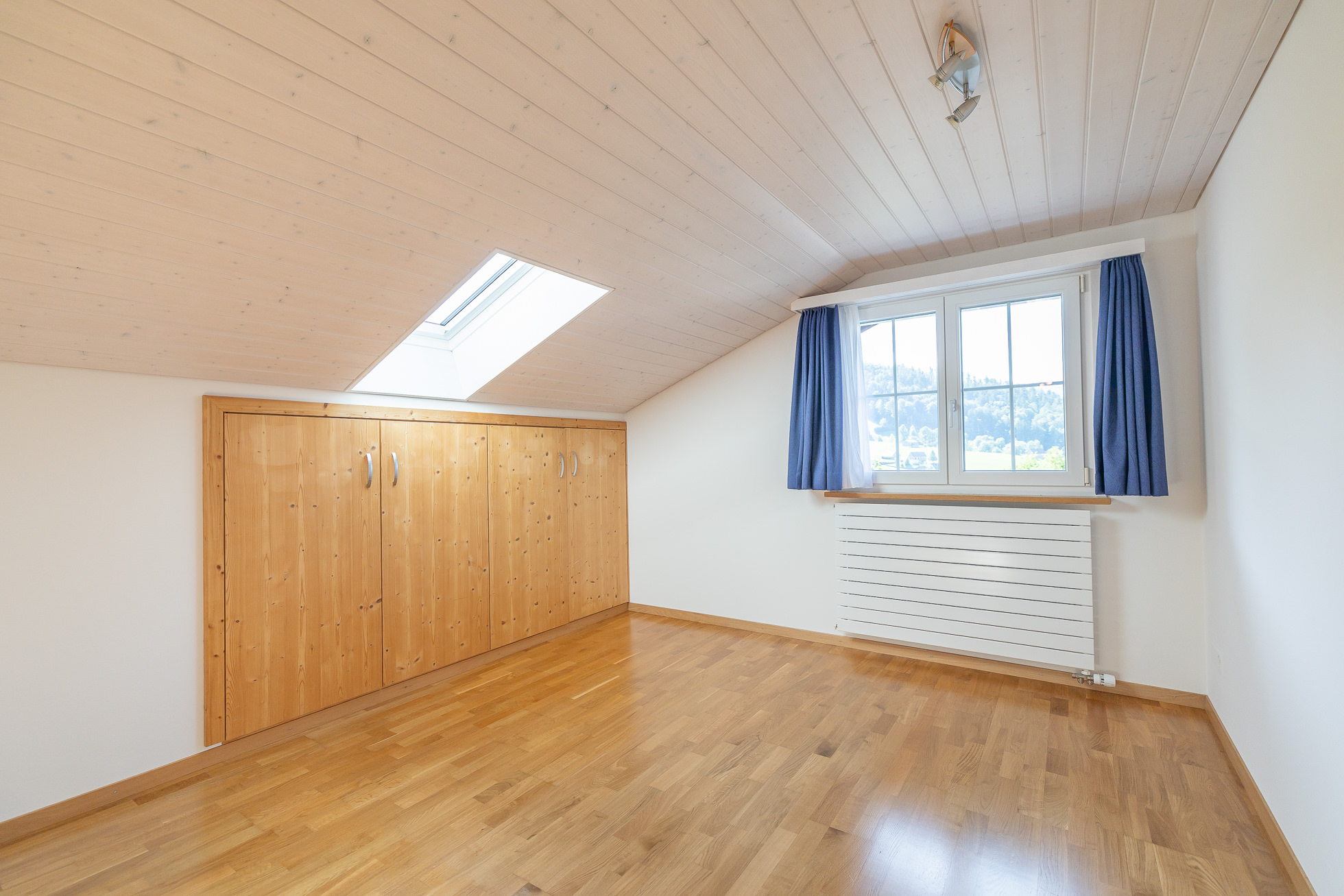 Helles Dachzimmer mit Holzverkleidung und Dachfenster