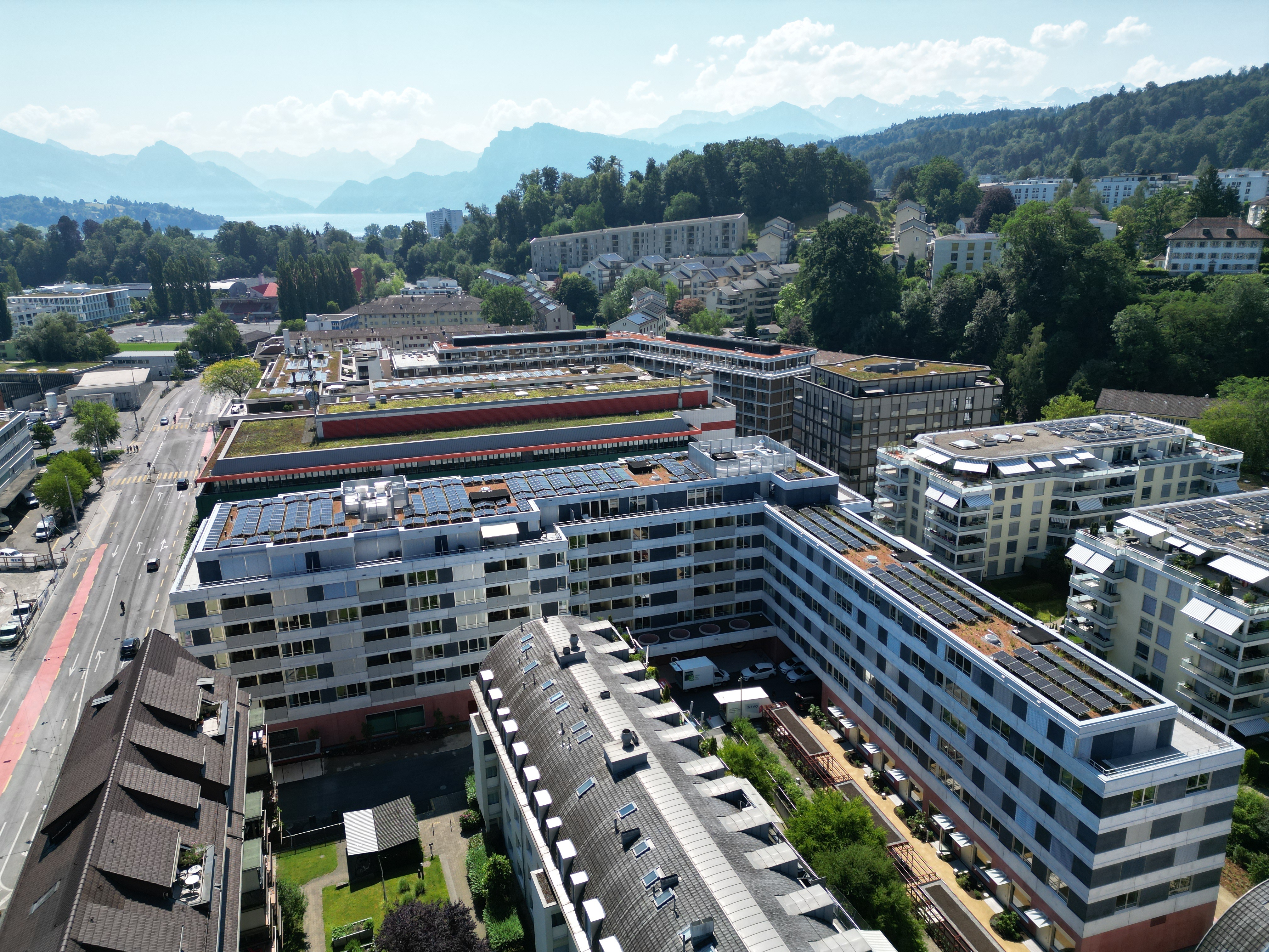 Luftaufnahme eines modernen Wohn- und Büroquartiers am See mit Bergen im Hintergrund