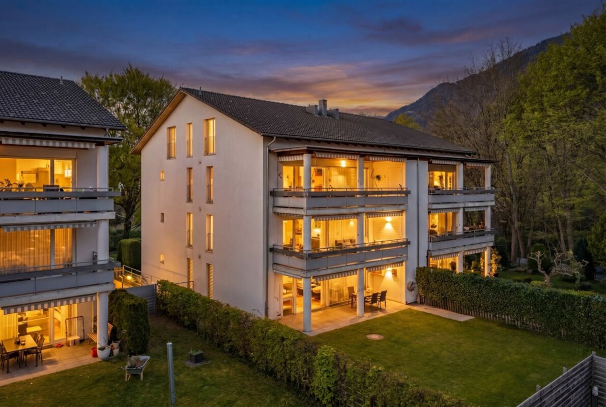 Wohnhaus mit beleuchteten Balkonen bei Dämmerung