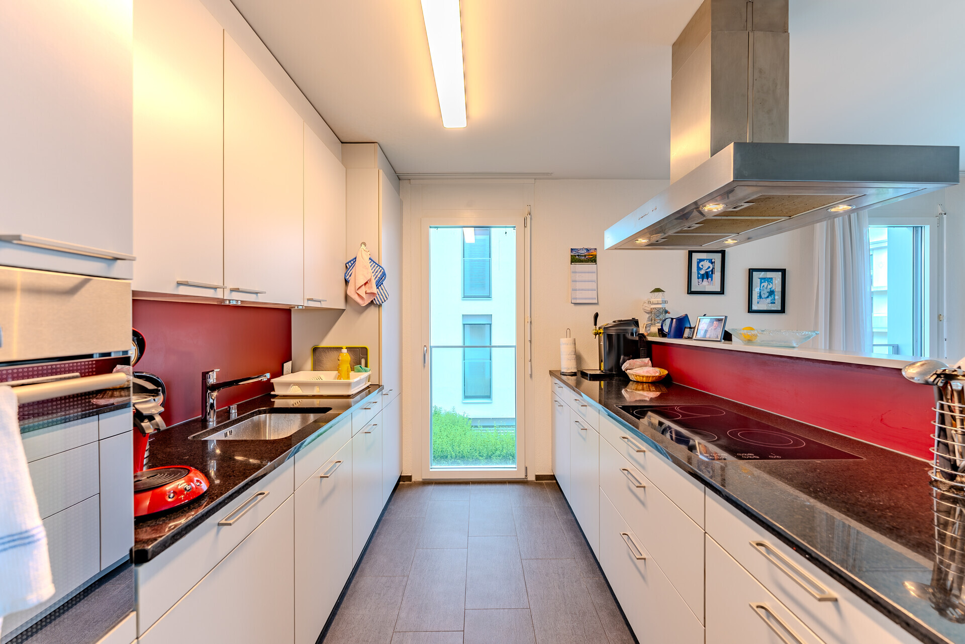 Schmale moderne Küche mit roter Rückwand