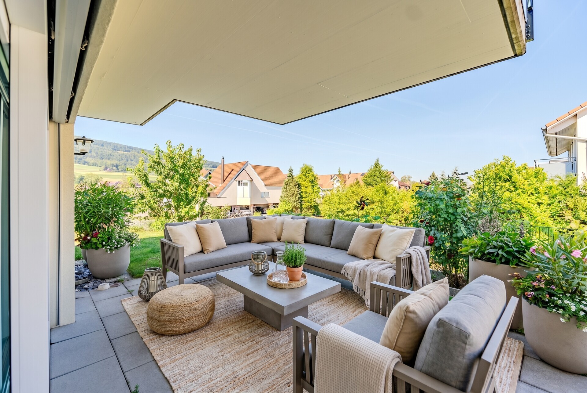 Große überdachte Terrasse mit Lounge-Möbeln und Gartenblick