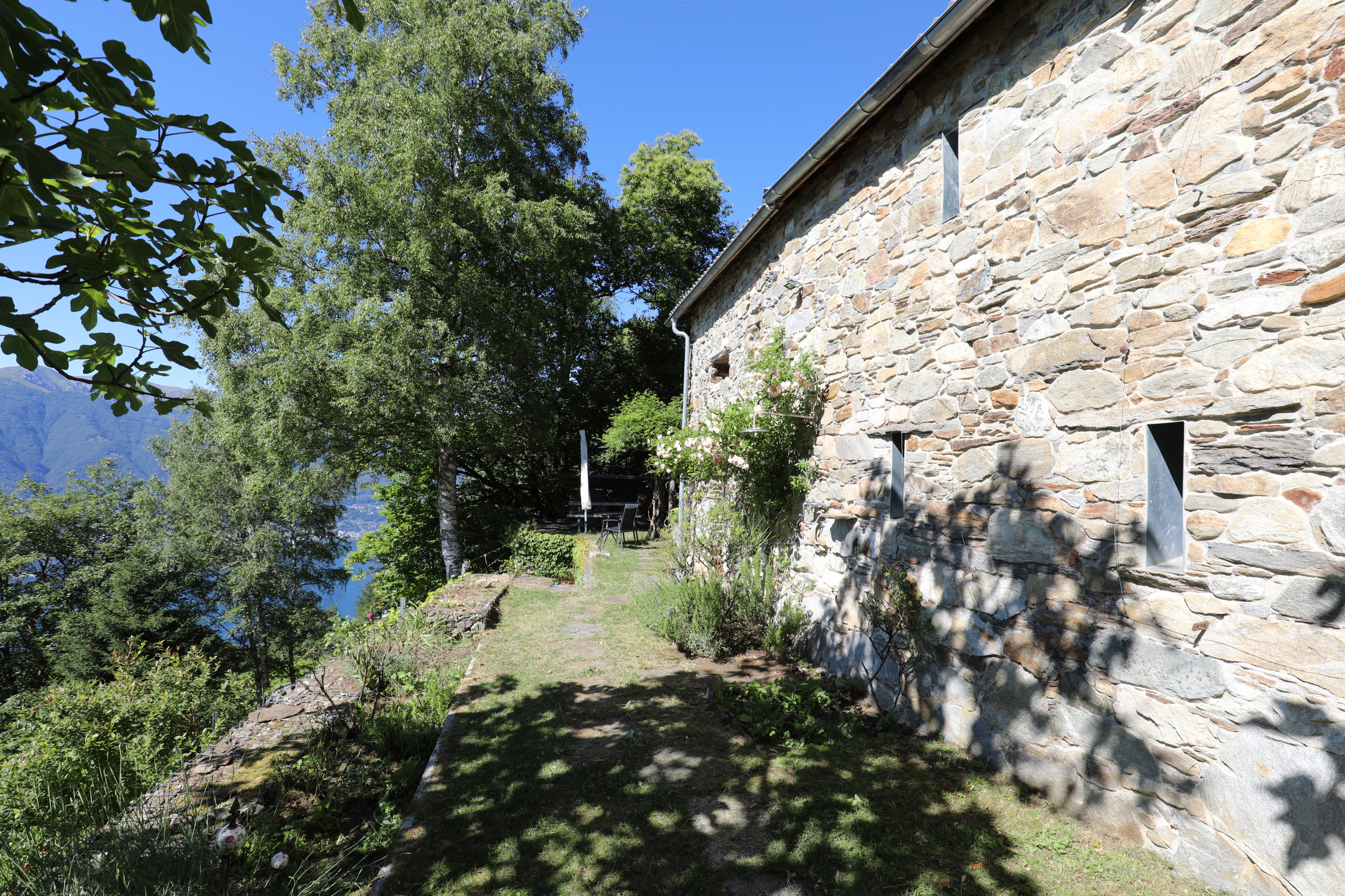 Steinhaus mit Gartenweg und Bergblick