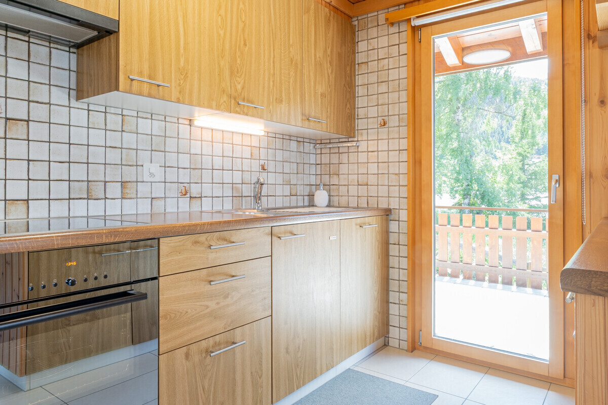 Helle Küche mit Holzelementen und Zugang zur Terrasse