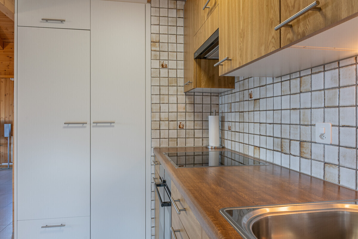 Küchenzeile mit Holzfronten und weißem Hochschrank