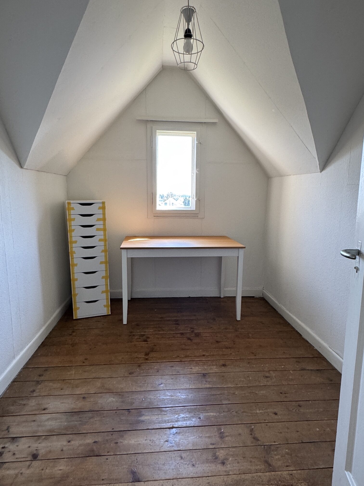 Dachzimmer mit Tisch und Fenster