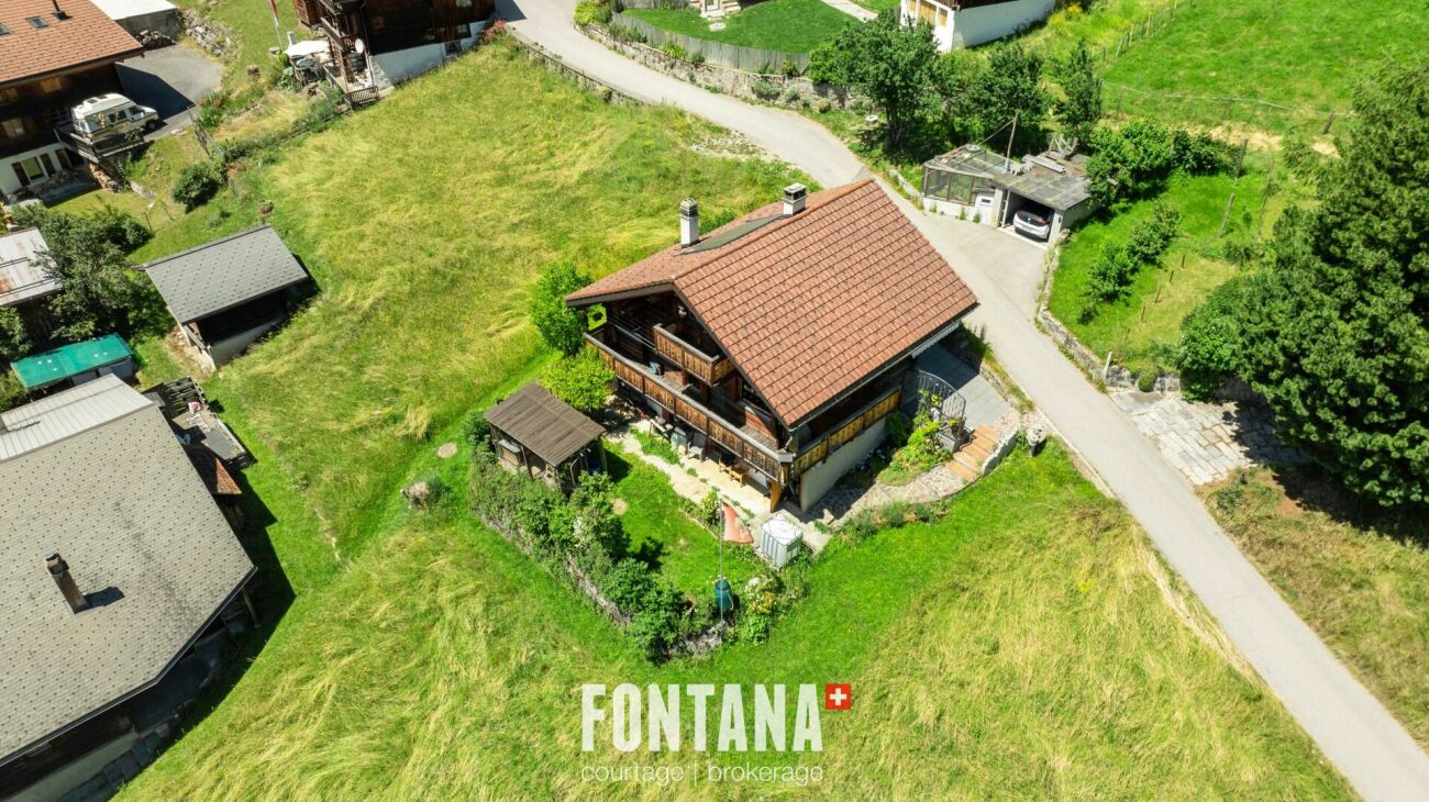 Luftaufnahme eines alpinen Wohnhauses mit großem Grundstück