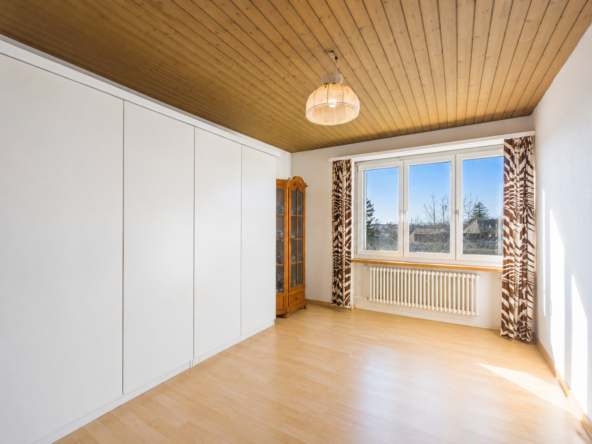 Heller leerer Raum mit Holzdecke und großem Fenster